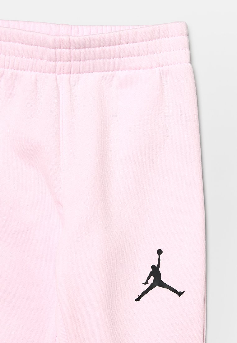 Pantalons de survêtement rose clair avec une taille côtelée. Dispose d'un logo Jumpman noir sur le côté gauche. Fabriqué en tissu doux. Coupe décontractée.