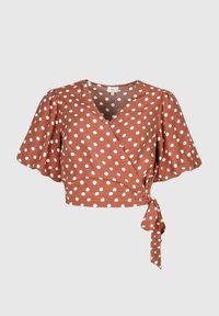 Top enveloppant marron à pois avec des manches bouffantes. Le tissu est léger avec un détail de nœud à la taille. Motifs circulaires blancs sur toute la surface.