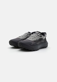 Scarpe da ginnastica nere e grigie con suola in gomma texturizzata, parte superiore in rete traspirante e sistema di allacciatura a contrasto. Presenta il logo sulla linguetta.
