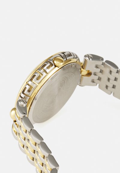 Kerek rozsdamentes acél óra arany szélű kerettel, láncsoros szíjjal és bonyolult mintázattal a széle mentén. Ezüst színű óralap.