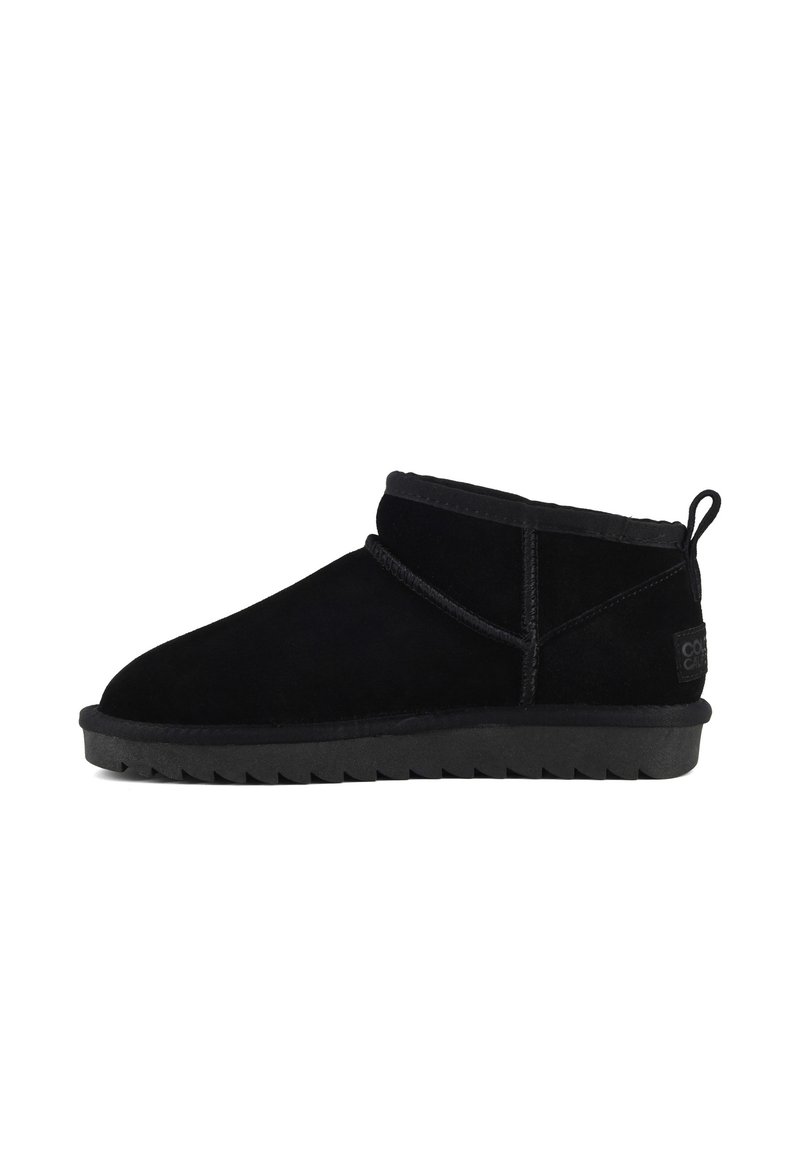 Botines de ante negro con puntera redondeada, tacón bajo y suela de goma texturada. Presentan un forro suave y un detalle de costura decorativa.
