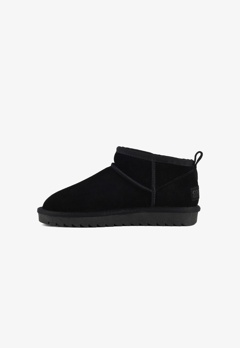 Botines de ante negro con puntera redondeada, tacón bajo y suela de goma texturada. Presentan un forro suave y un detalle de costura decorativa.