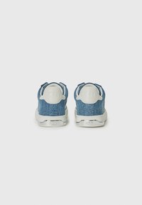 Jeans sneakers med en lys blå tekstur, hvit gummisåle og polstret hælflik. Har DKNY-logo på hælen. Høy-top design.