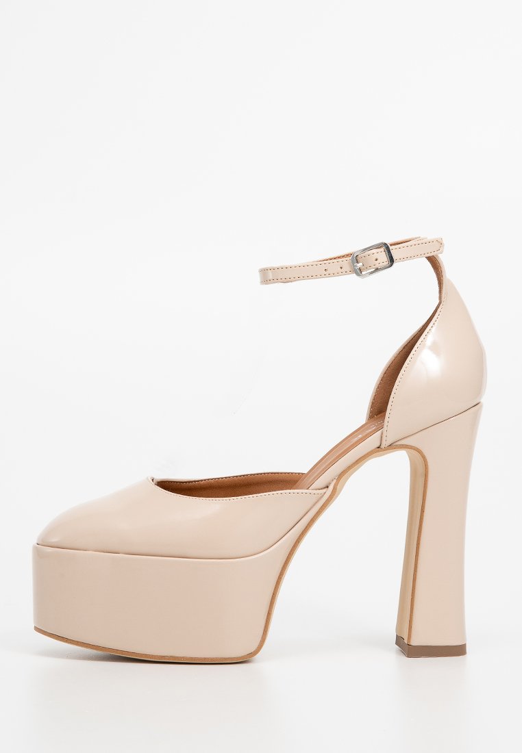 Beigefarbene Lackleder-Plateau-Pumps mit Knöchelriemen und silberner Schnalle, geschlossener Zehenbereich und klobigem Absatz.