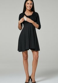 Black dress with a fitted bodice and flared skirt, featuring a polka dot pattern. Three-quarter sleeves and a twist detail at the bust.