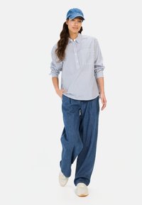 Gestreiftes Button-up-Hemd in Blau und Weiß, lockere Denim-Hose und eine blaue Denim-Mütze. Lässiger Stil mit lockerer Passform und minimalen Details.