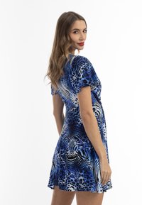 Rochie scurtă albastră dintr-un material moale, cu un model vibrant de imprimeu animalier în diverse nuanțe de albastru și alb. Fustă evazată.