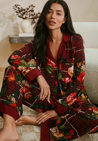 Red plaid pajama set with floral accents, featuring a button-up top and elastic waist pants, made from soft fabric with a smooth texture.