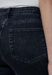 Donker denim high-waisted jeans met een achterzak, subtiele vervaging en een klassieke vijf-pocket stijl. Soepele textuur en hoge rekbaarheid.
