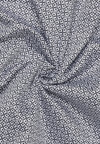 Cotton fabric featuring a repeating geometric pattern in black and white, with a smooth texture and draped appearance.