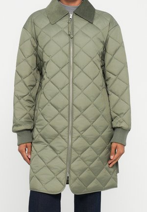 Veste longue matelassée vert olive avec surpiqûres en forme de losange, fermeture éclair à l'avant, poignets côtelés et col en velours côtelé vert foncé.