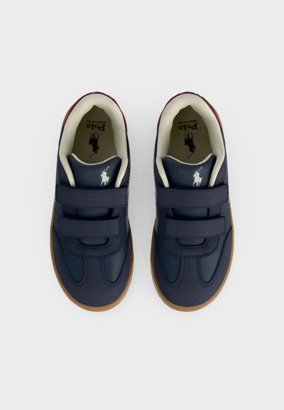 Ζευγάρι σκούρα μπλε αθλητικά Polo Ralph Lauren με καφέ σόλες και διπλά λουράκια βέλκρο, από πάνω σε λευκό φόντο.