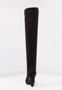 Black, suede, over-the-knee boot with a tapered shape, high stiletto heel, and smooth texture. Features a contoured design at the back.