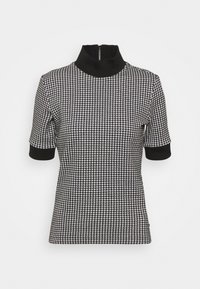 Sort og hvid houndstooth kortærmet top med høj krave og lynlås, der har sort kant ved ærmer og hals.