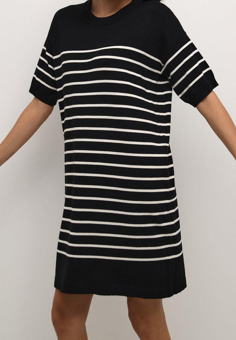 Czarna i biała sukienka koszulowa w paski z krótkimi rękawami, prążkowanym dekoltem, bocznymi rozcięciami i luźnym krojem. Teksturowana dzianina.