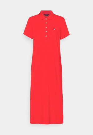 Robe polo rouge à manches courtes avec col, cinq boutons blancs et petit logo noir et blanc sur le côté gauche de la poitrine.