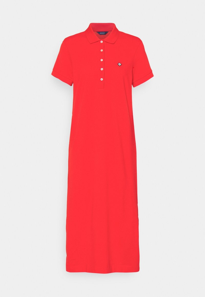 Robe polo rouge à manches courtes avec col, cinq boutons blancs et petit logo noir et blanc sur le côté gauche de la poitrine.