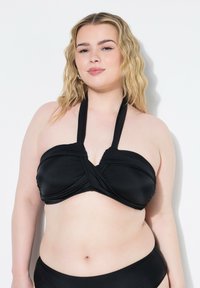 Top bikini nero con un design incrociato davanti, realizzato in materiale morbido ed elastico, dotato di spalline a halter e finitura senza cuciture.