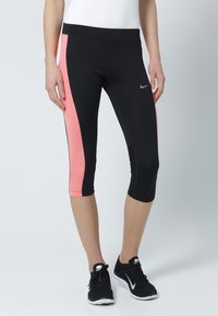 Black capri leggings featuring a pink side panel, made of stretch fabric, with a smooth texture and a discreet Nike logo on the front.