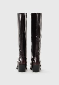 Bottes en cuir marron montantes avec une finition lisse, un talon carré rectangulaire et un détail de fermeture éclair à l'arrière.