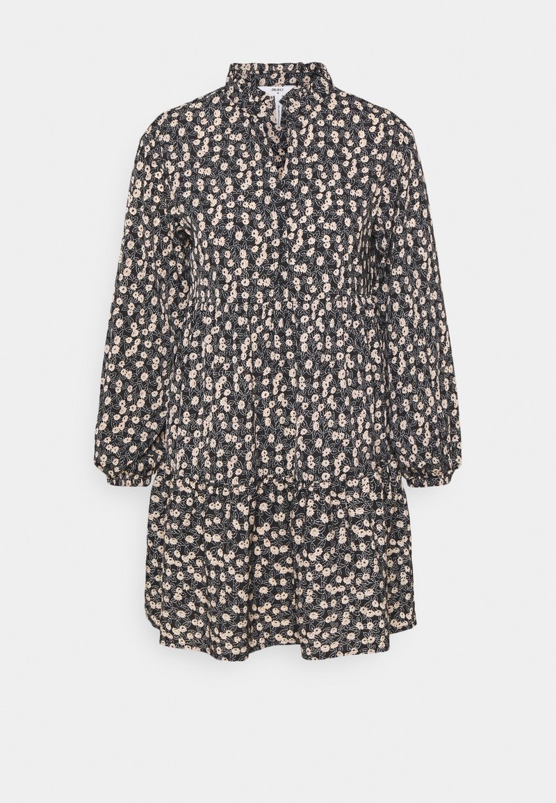 Robe noire à fleurs avec des manches longues, un col et des volants froncés. Présente de petits motifs de fleurs crème sur le tissu.