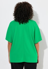 Grön, överdimensionerad kortärmad topp med rak nederkant och mjuk textur, med en enkel design och inga synliga mönster eller dekorationer.
