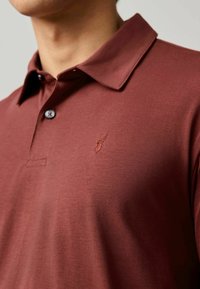 Burgundowa koszulka polo z krótkim rękawem, miękka w dotyku, z dwoma guzikami i małym haftowanym logo homara na piersi.