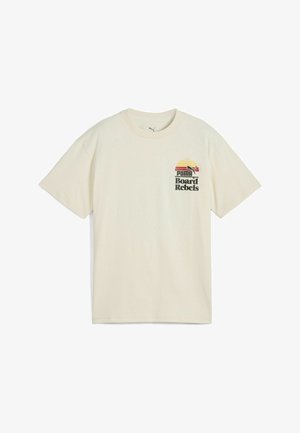 Camiseta de algodón crema de manga corta con escote redondo. Presenta una colorida impresión gráfica con "PUMA Board Rebels" en el frente.