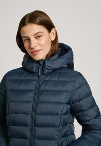 Veste en duvet navy avec capuche, design matelassé horizontal, fermeture éclair à l'avant et texture douce et lisse.