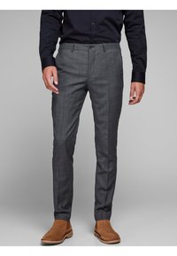 Grijze op maat gemaakte broeken met een gestructureerd patroon, voorzien van een knoopsluiting, zijzakken en een slim fit ontwerp, gecombineerd met bruine laarzen.