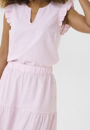 Mujer con vestido sin mangas de rayas verticales en rosa pálido y blanco, con volantes en los hombros y cintura elástica, levantando un brazo.