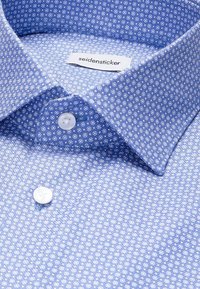 Chemise bleue à motif circulaire blanc, boutons blancs et étiquette "seidensticker" à l'intérieur du col.