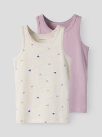 Zwei ärmellose Baumwoll-Tanktops für Kinder, eines lila und eines cremefarben mit mehrfarbigen Herzmotiven, flach auf einem grauen Hintergrund ausgelegt.