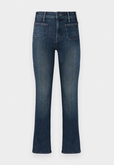 Jean en denim bleu foncé avec une coupe ajustée, présentant une taille mi-haute, deux poches arrière et un léger délavage autour des cuisses et des ourlets.