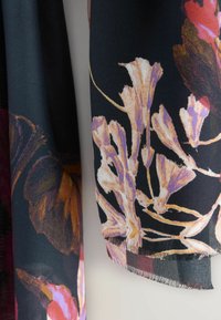 Schwarzer Stoffschal mit floralen Mustern in Rosa, Lila und Orangetönen, mit fransigem Rand und weicher Textur.