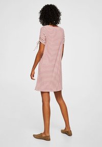 Pasiasta sukienka z krótkim rękawem w kolorze czerwonym i białym, o luźnym kroju oraz regulowanych wiązaniach na rękawach. Miękka tkanina, sięgająca do kolan.