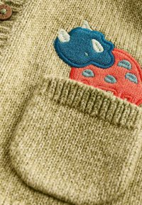 Pull en maille vert clair avec tissu texturé. Comprend une poche plaquée et un motif brodé d'un nuage bleu et d'une fraise rouge.