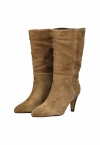 Botas de ante marrón hasta la rodilla con punta afilada y tacón de stilettos delgado. Textura suave con detalle de costura vertical a lo largo del tubo.