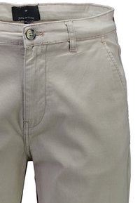 Beżowe bawełniane chinosy o klasycznym kroju, z zapięciem na guzik, szlufkami na pasek i przednimi kieszeniami. Gładka faktura i neutralny kolor.