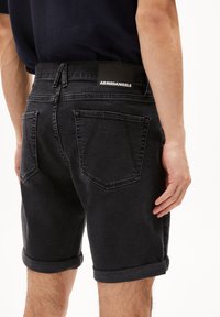 Zwarte denimshorts met een opgerolde zoom, voorzien van een leren label op de achterkant van de tailleband. Twee achterzakken met een diamantvormig ontwerp.