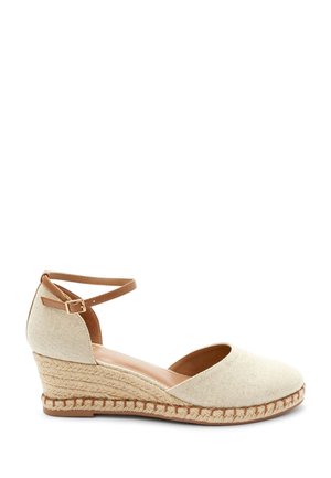 Sandały espadryle na koturnie z teksturowanej beżowej tkaniny, z paskiem wokół kostki i dekoracją z juty wokół podeszwy. Gładkie brązowe wnętrze.