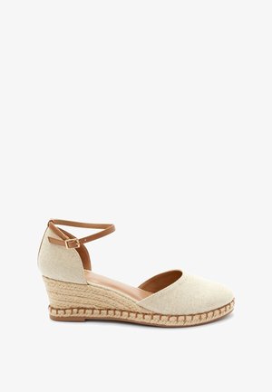 Sandały espadryle na koturnie z teksturowanej beżowej tkaniny, z paskiem wokół kostki i dekoracją z juty wokół podeszwy. Gładkie brązowe wnętrze.