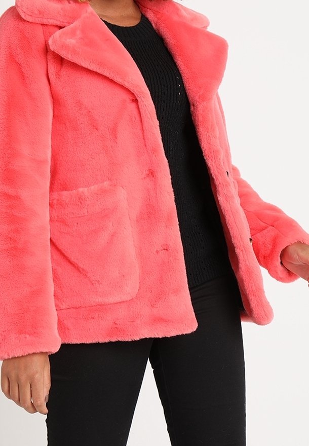 Faux fur, bright pink coat with a notched collar, front pocket, and button closure. Worn over a black knit sweater. Soft texture.