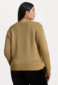 Senčeno rumeno pleteno pulover z teksturirano pletenino na ramenih in rebrastim robom. Ima sproščen kroj in dolge rokave.