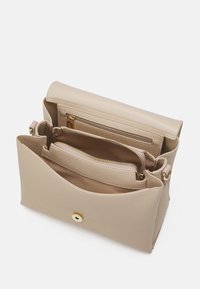 Bolso de mano de cuero beige con un diseño estructurado, múltiples compartimentos, bolsillos con cremallera y un cierre de botón a presión con acento dorado.