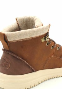 Stivaletto in pelle marrone con fodera interna beige, punta rotonda, cuciture scure a contrasto, occhielli in metallo e suola in gomma texture.