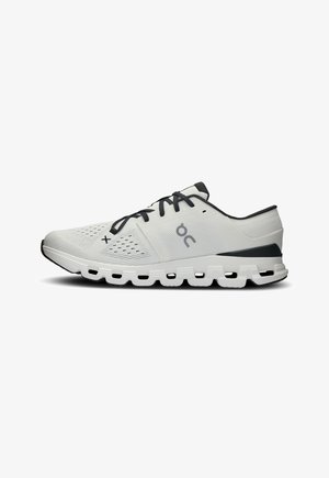 Zapatilla deportiva de correr blanca y negra con suela acolchada, parte superior de malla, cordones negros y logo "On" en el lateral.