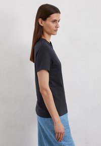 T-shirt nera a maniche corte realizzata in tessuto morbido, con collo rotondo, vestibilità slim e texture liscia, abbinata a una gonna blu con texture.