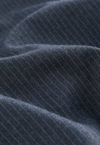 Mörkblått tyg med fina vertikala ränder. Mjuk textur med en något fluffig finish. Bomullsblandning med en subtil lyster från de vävda trådarna.