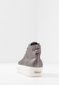 Höga sneakers i metallgrått material med krämfärgade snören, vit gummisula och märkets hälrem med "Nizza"-logotyp.